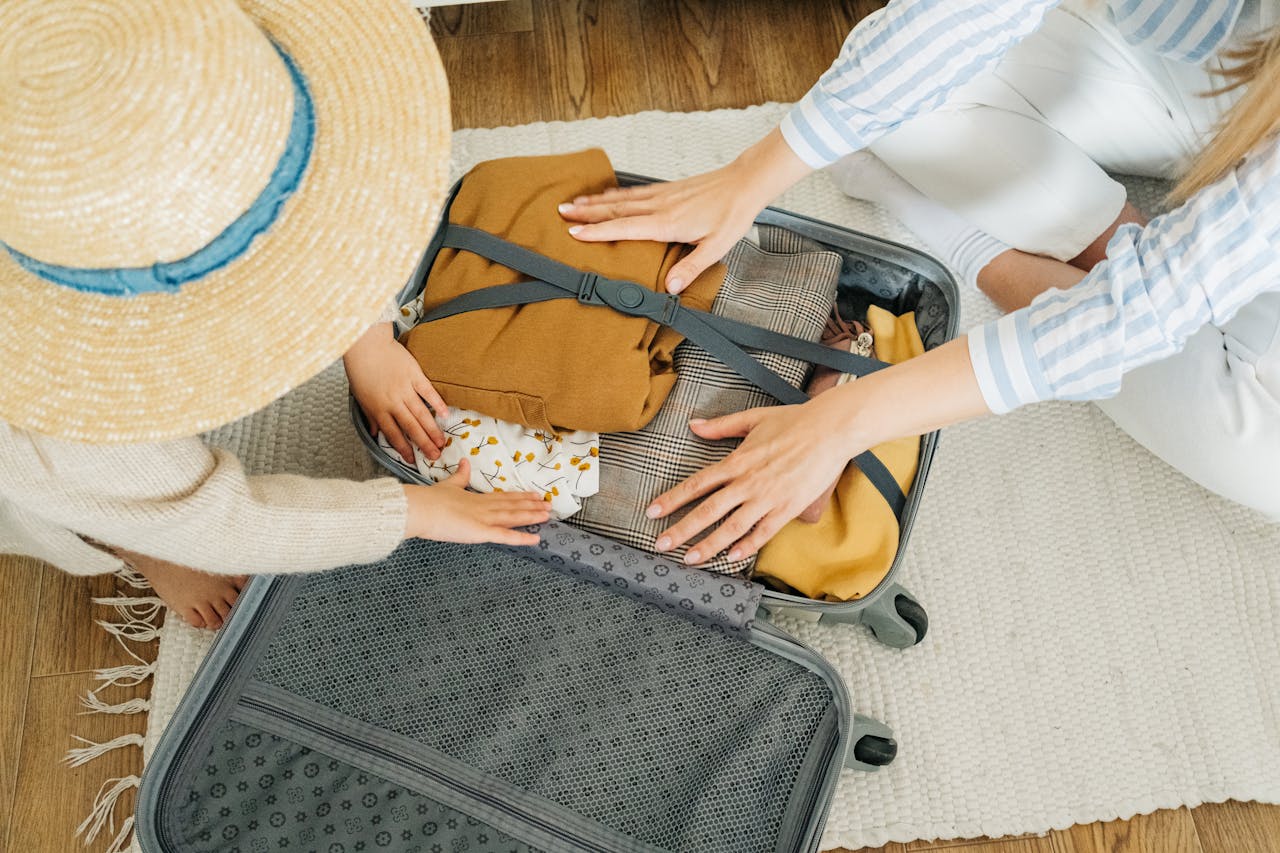 about-us A woman and child pack clothes in a suitcase, preparing for a vacation.